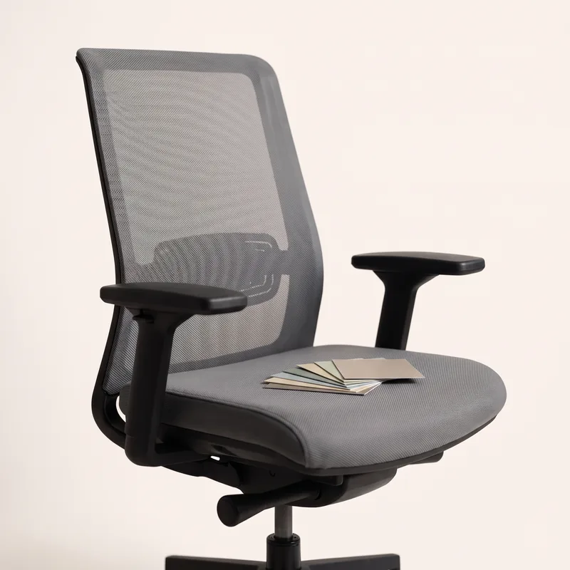 An empty office chair, a fan of paper colour swatches on the seat