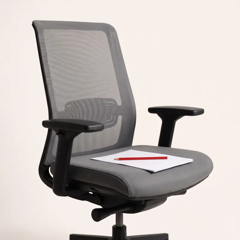 An empty office chair, a red pencil on a folded page on the seat