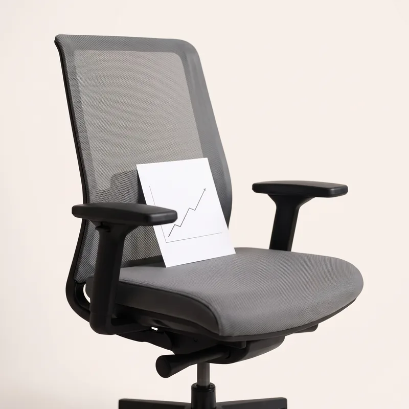 An empty office chair, a small paper chart propped on the seat